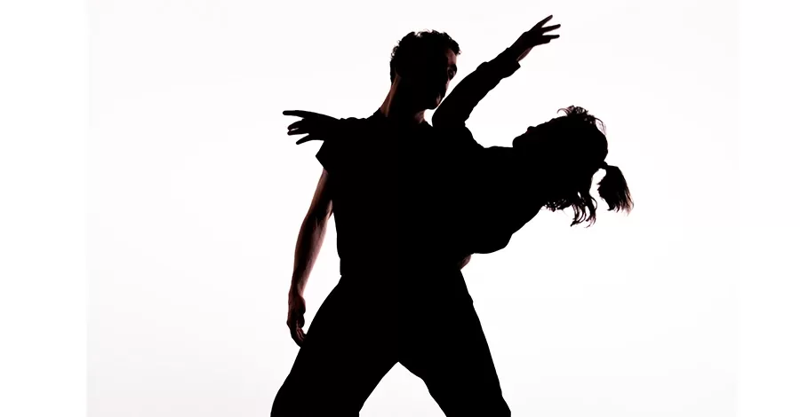 dos bailarines abrazados en un plano medio, fondo blanco y a contraluz