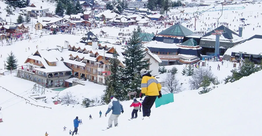 Paisaje de Bariloche donde se ve gente esquiando y las casas del pueblo detrás